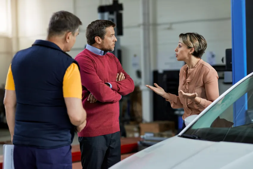 displeased woman having argument with her husband about car repair workshop 1