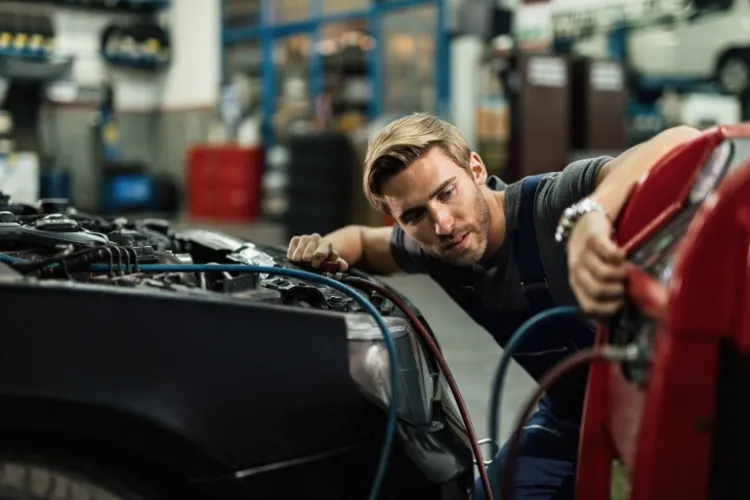 young auto mechanic using compressor while maintaining ac unit car workshop 768x512 1